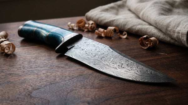 Close-up of a pattern-welded Damascus knife blade showing wavy light and dark steel bands