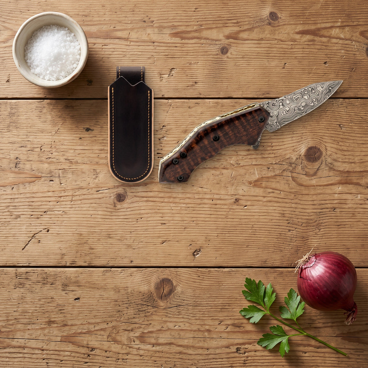 Creek 6.2" Damascus Pocket Knife | Snakewood, with the Crownridge belt slip in use